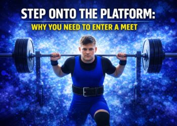 Beginner powerlifter stepping onto the platform with a barbell during a first powerlifting meet attempt