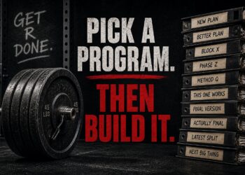 Powerlifting barbell with stacked plates beside binders labeled training programs, illustrating consistency vs program hopping in powerlifting