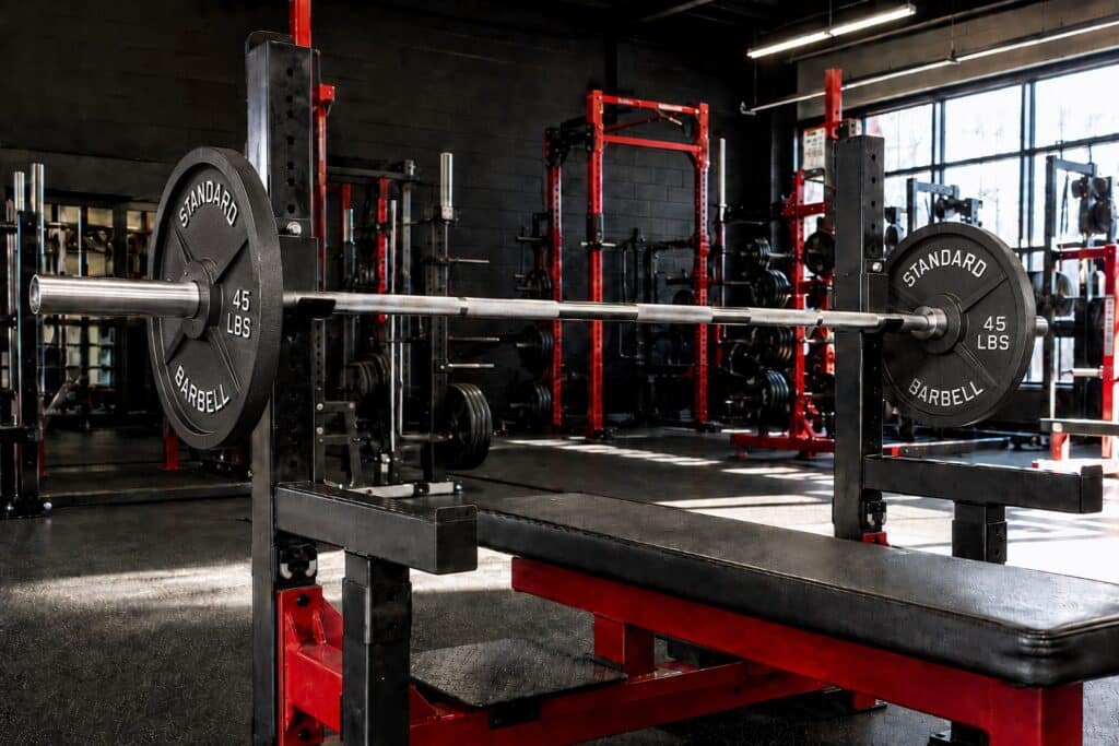 Close-grip bench press setup with a loaded barbell on a flat bench in a powerlifting gym, demonstrating a key exercise for building stronger triceps, improving bench press strength, and increasing upper-body power.