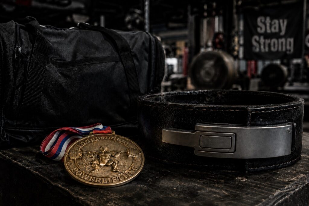 Powerlifting belt, competition medal, and gym bag displayed in a strength training gym, symbolizing dedication, achievement, and long-term success in powerlifting.
