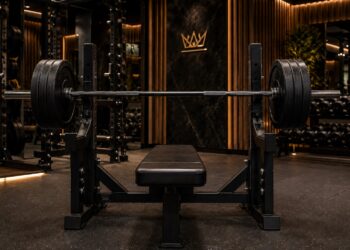 Powerlifting bench press setup with loaded barbell, flat bench, and rack in a luxury strength gym, highlighting control, stability, and grip for a bigger bench press.