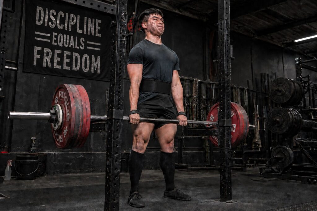 Powerlifter locking out a heavy deadlift to show the difference between supplemental and accessory lifts for powerlifting strength.