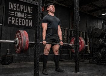 Powerlifter locking out a heavy deadlift to show the difference between supplemental and accessory lifts for powerlifting strength.